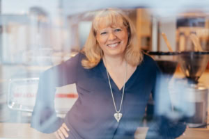 Freundliche Geschäftsfrau in einem modernen Büro - photoart hübner business Lächelnde Frau in Businesskleidung vor einem Bürohintergrund.