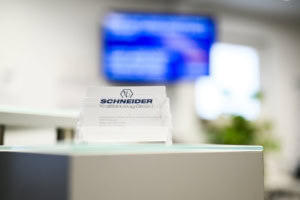Schneider Firmenname auf Visitenkarte - photoart hübner business Visitenkarte von Schneider Kraftfahrzeug GmbH auf einem Schreibtisch.