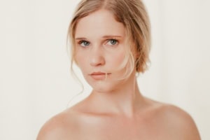 Porträt einer jungen Frau mit natürlichem Make-up, Blick direkt in die Kamera, helles Hintergrundbild. - photoart hübner business Junge Frau mit natürlichem Aussehen, professionelles Business-Porträt.