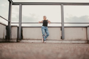 Moderne Businessfotografie auf einem Dachgeschoss. - photoart hübner business Frau posiert selbstbewusst vor einer großen Fensterfront mit Blick in den Himmel.