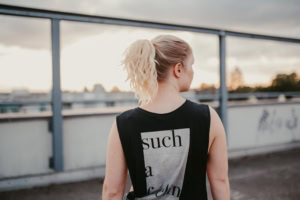 Moderne Businessfrau auf der Dachterrasse - photoart hübner business Frau mit sportlicher Kleidung blickt auf die Stadt bei Sonnenuntergang.