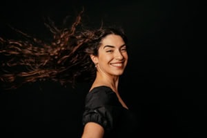 Moderne Businessfrau mit lockigem Haar vor schwarzem Hintergrund - photoart hübner business Selbstbewusste Geschäftsfrau lächelt bei Business- und Karrierefotos, ideal für Personal Branding un.