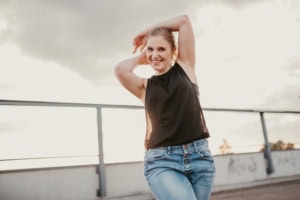 Porträt einer lachenden jungen Frau auf einem Dach, Business- und Personal Branding. - photoart hübner business Lächelnde Frau in casual Business-Kleidung auf einem Dach mit Stadtblick.
