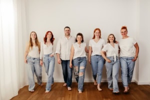 Fotografen-Team von Photoart Hübner Business in entspannter Atmosphäre - photoart hübner business Teamfoto von Photoart Hübner Business mit sieben Personen in weißen Oberteilen und Jeans.