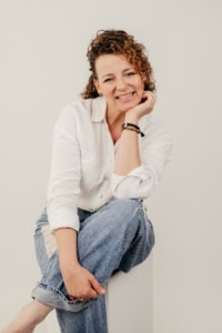 Fotografie einer lächelnden Frau in entspannter Pose, Fokus auf Business-Portrait. - photoart hübner business Lächelnde Frau in Business-Umgebung, professionelles Portrait für Unternehmenspräsentation.