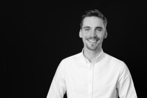 Mann in Business-Kleidung, professionell und freundlich, auf schwarzem Hintergrund.