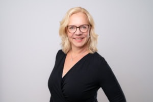 Professionelle Business-Fotografie einer Frau mit Brille, die Selbstvertrauen und Kompetenz ausstrah.