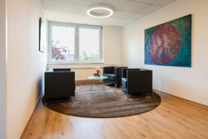 Wartezimmer mit stilvollen schwarzen Sesseln und abstrakter Kunst im modernen Büro.