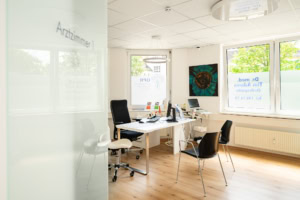 Büro mit Schreibtisch, Stühlen und großen Fenstern, ideal für Business-Fotos.