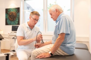 Hautarzt prüft Hand eines Patienten in der dermatologischen Praxis.