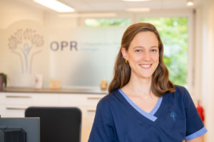 Zahnarztpraxis mit freundlicher Mitarbeiterin, professionelle Zahnbehandlung in angenehmer Atmosphär.