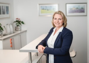 Professionelle Businessfotografie im Büro - photoart hübner business Frau in Businesskleidung lächelt im modernen Büro, ideal für Unternehmens- und Personal Branding Fot.