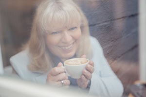 Frau trinkt Kaffee im Café, entspannt und glücklich, Genussmoment.
