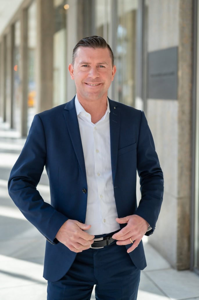 Moderne Business-Porträtfotografie eines Mannes in Anzug vor urbaner Kulisse - photoart hübner business Business-Porträt eines professionellen Mannes in Anzug vor moderner Stadtarchitektur.