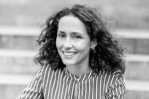 Porträt einer lächelnden Frau in Businesskleidung, professionelle Unternehmensfotografie. - photoart hübner business Frau mit lockigem Haar, freundliches Lächeln, Businessfotos für Personal Branding.