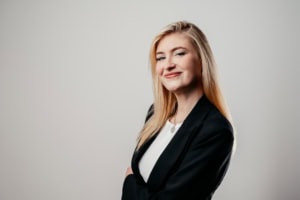 Selbstbewusste Businessfrau in professionellem Outfit, lächelnd und zuversichtlich.