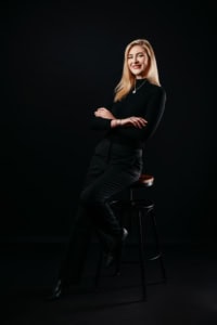 Professionelles Portrait einer jungen Frau vor schwarzem Hintergrund.