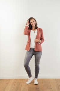 Moderne Businessfotografie Frau vor weißer Wand - photoart hübner business Frau in Businessoutfit posiert vor neutralem Hintergrund, ideal für Unternehmens- und Personal Brand.