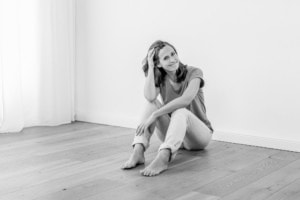 Businessfotografie Portrait einer Frau in entspannter Pose - photoart hübner business Frau sitzt entspannt auf Holzboden, natürliche Beleuchtung, Businessfotografie.