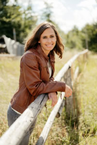 Moderne Businessfotografie im Freien - photoart hübner business Frau in Businesskleidung lehnt an Holzsteg im Grünen.