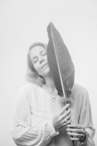 Porträt einer Frau mit geschlossenen Augen, die ein großes Blatt hält. Elegante Business- und Personal Branding-Fotografie. - photoart hübner business Frau hält ein großes Blatt vor das Gesicht, symbolisiert Natürlichkeit und Individualität in der Bus.