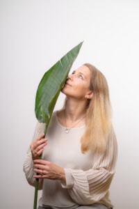 Businessfotografie mit natürlichem Look - photoart hübner business Frau hält große grüne Blätter vor das Gesicht, kreative Businessfotografie.