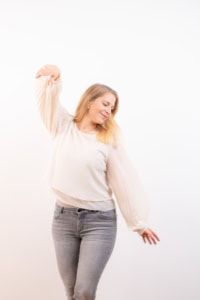 Businessporträt mit natürlichem Lächeln und entspannter Haltung - photoart hübner business Porträt einer jungen Frau in Businesskleidung für professionelle Personal Branding Fotos.