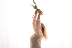 Businessfotografie mit natürlicher Ausstrahlung und persönlicher Note - photoart hübner business Frau hält eine Blume hoch, symbolisiert Kreativität und Individualität in der Businessfotografie.