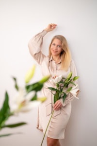 Businessfotografie Portrait mit Blumen - photoart hübner business Frau hält Blumen und lächelt vor weißem Hintergrund.