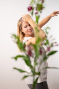 Moderne Businessporträtaufnahme mit Blumen im Vordergrund - photoart hübner business Porträt einer Frau vor neutralem Hintergrund, umgeben von Blumen, für professionelle Businessfotogra.
