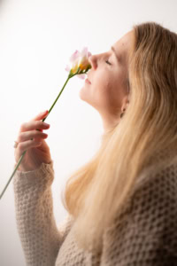 Stilvolle Businessfotografie mit natürlichem Ausdruck - photoart hübner business Porträt einer Frau mit Blume, Fokus auf Persönlichkeit und Authentizität.
