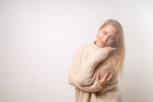 Businessporträt einer jungen Frau in gemütlicher Kleidung - photoart hübner business Frau in Pullover posiert nachdenklich vor weißem Hintergrund.