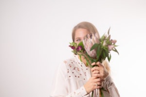 Moderne Businessfotografie mit Blumenarrangement - photoart hübner business Frau hält Blumen vor Gesicht, Fokus auf Business- und Personal Branding Fotos.
