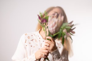 Businessfotografie mit Blumen, professionelle Portraitaufnahme - photoart hübner business Porträt einer Frau mit Blumen, ideal für Business- und Personal Branding Fotos.