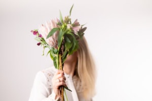 Blumen-Motiv für Businessfotografie - photoart hübner business Frau mit Blumenstrauß verdeckt Gesicht, professionelles Businessfoto.