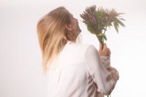 Businessfotografie mit Blumenstrauß - photoart hübner business Frau hält einen Blumenstrauß in Businesskleidung, professionell und freundlich.