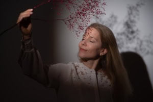 Businessfotografie mit natürlichem Ausdruck und eleganter Pose - photoart hübner business Frau hält Zweig mit roten Beeren, professionelles Businessfoto, natürliche Ausstrahlung.