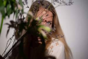 Moderne Businessfotografie mit natürlichem Ausdruck - photoart hübner business Frau hinter Blumenarrangement, professionelle Business- und Personal Branding Fotos.