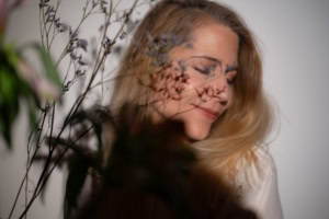 Businessporträt mit Blumen im Vordergrund - photoart hübner business Frau mit geschlossener Augen und Blumen im Vordergrund, professionelles Businessfoto.