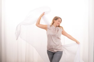 Businessfotografie mit lebendiger Ausdruckskraft und natürlichem Licht - photoart hübner business Frau posiert mit weißen Stoffen vor hellem Hintergrund, ideal für Unternehmens- und Personal Brandin.