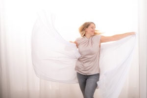 Selbstbewusste Frau mit weißen Stoffen, kreative Unternehmensfotografie - photoart hübner business Frau posiert mit weißen Stoffen vor hellem Hintergrund, ideal für Business- und Personal Branding Fo.