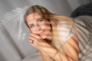 Businessfotografie Portrait mit natürlichem Licht und freundlichem Ausdruck - photoart hübner business Frau mit blonden Haaren und blauen Augen, lächelnd, im natürlichen Licht fotografiert.