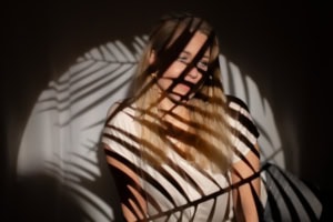 Businessfotografie mit kreativen Licht- und Schatteneffekten - photoart hübner business Frau mit Schattenmuster auf Gesicht und Kleidung, kreative Businessfotografie.