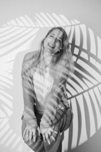 Businessfotografie mit natürlichem Lächeln - photoart hübner business Attraktive Frau in Businesskleidung vor einer stilvollen, schattierten Hintergrundwand.