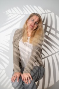 Businessfotografie Portrait mit natürlichem Licht und kreativen Schatteneffekten - photoart hübner business Porträt einer Frau in Businesskleidung vor einem weißen Hintergrund mit Schatten einer Pflanzenblätt.