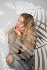 Businessfotografie Portrait mit natürlichem Licht und kreativen Schatten - photoart hübner business Frau in Businesskleidung vor Schatten einer Palme, professionell und selbstbewusst.