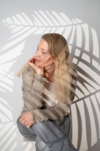 Businessporträt mit natürlichem Licht und Schatteneffekt - photoart hübner business Frau in Businesskleidung vor Schatten einer Palme, professionelles Personal Branding.