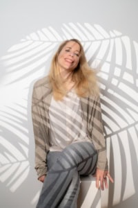 Lächelnde Frau bei Businessfotografie - photoart hübner business Frau posiert vor einer weißen Wand mit Schatten einer Palme, ideal für Unternehmens- und Personal Br.