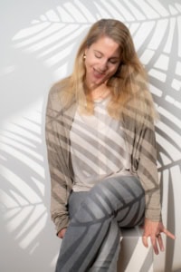 Businessporträt mit natürlichem Lächeln - photoart hübner business Frau in Businesskleidung vor weißer Wand mit Schattenmuster, professionelles Personal Branding.