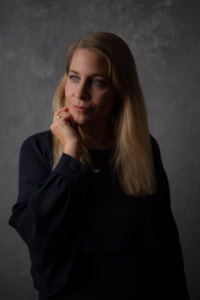 Businessfotografie Portrait einer Frau vor grauem Hintergrund - photoart hübner business Frau in dunklem Outfit für professionelle Business- und Personal Branding Fotos.